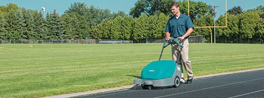 Tennant S5 walk-behind sweeper being used on running track