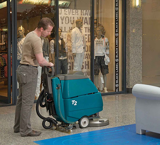 cleaning crew using Tennant walk behind floor scrubber in main area of retail store