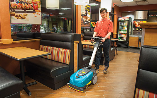 cleaning staff using CS5 walk behind floor scrubber in convenience store to clean floor