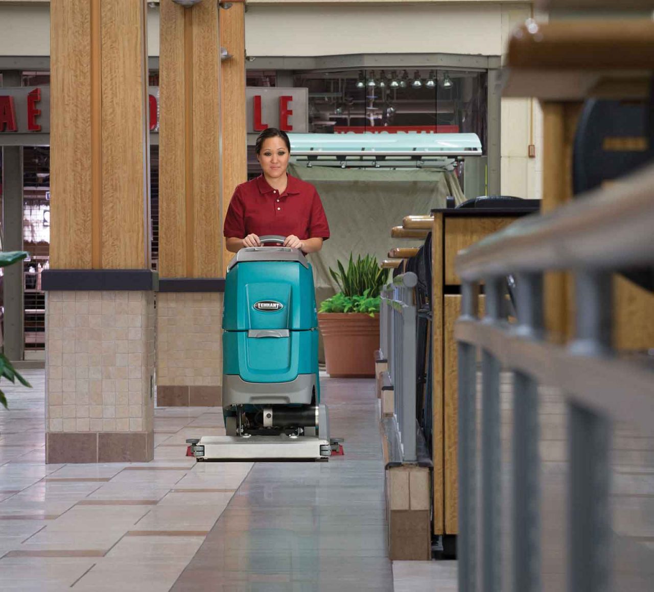un limpiador que utiliza la restregadora de pisos de operador caminando para limpiar un centro comercial