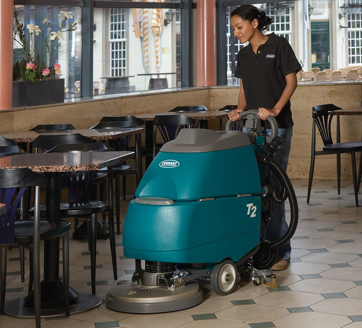 Uma trabalhadora efetua a manutenção de um pavimento de betão polido com uma auto lavadora.
